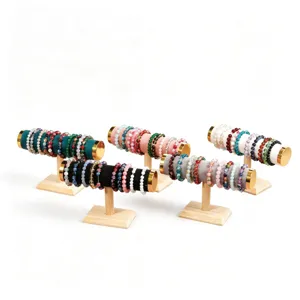 Wooden jewelry display stands set with velvet cylinders and colorful beaded bracelets.