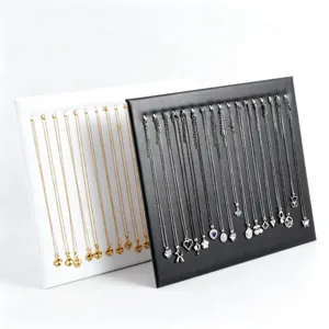 Ensemble de présentoirs à bijoux noirs et blancs présentant d'élégants colliers en or et argent.