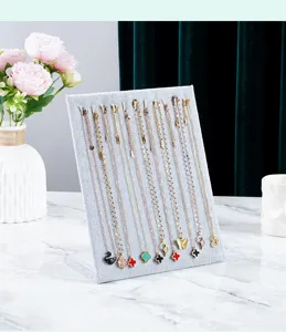Presentoir de collier en velours gris avec plusieurs colliers pendentifs elegants.