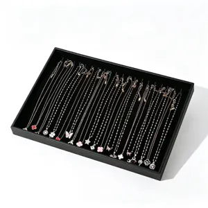 Plateau de présentation élégant pour colliers en cuir noir avec délicats pendentifs.