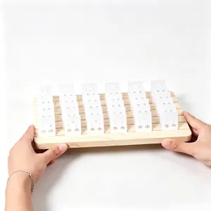 Houten sieradendisplay-tray sleuven en witte kaarten voor het presenteren van oorbellen en knopjes.