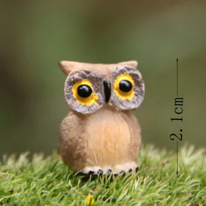 Detailopname van een miniatuur hars uil beeldje op groen mos, ideaal voor vetplanten tuindecoratie.