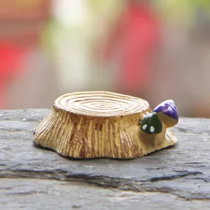 Miniature resin tree stump figurine with cute small colorful mushrooms, detailed macro shot.