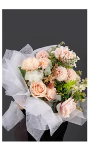 Bouquet de fleurs artificielles roses emballé dans du papier filet blanc, détails floraux élégants.