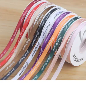 Detailed shot of colorful 1cm fabric ribbon rolls with printed text for gift wrapping and DIY crafts.