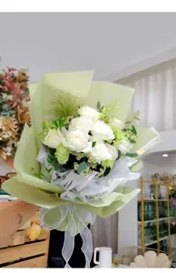 Elegant witte rozen boeket verpakt in lichtgroen papier met wit striklint voor cadeaus