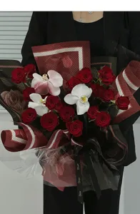 Detailansicht eines exquisiten Rosen- und Orchideen-Blumenstraußes mit bedrucktem Band.