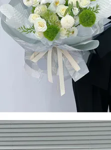 Detailansicht eines weißen Rosenstrauchs in strukturiertem Blumenpapier mit eleganter Schleife.