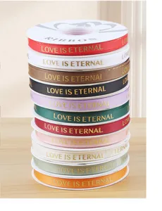 Close up of colorful grosgrain ribbon rolls featuring love is eternal gold stamped text.