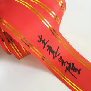 Cinta de banner de celebración roja con bordes dorados y caligrafía para grandes aperturas.
