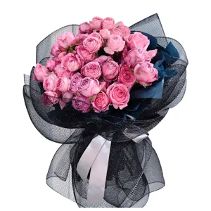 Superbe bouquet de roses roses enveloppé dans un filet noir stylé avec ruban blanc.