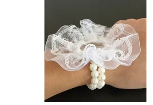 Primer plano detalle de flor de muñeca de encaje blanco con doble pulsera de perlas.