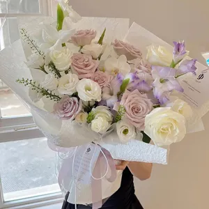 Raffinato bouquet di fiori in carta testurizzata artigianale con rose pastello e nastri decorativi.