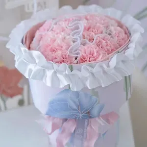 Rosa Nelken Blumen Geschenkkarton mit weißem Rüschenspitzenrand und Dekoband für Anlass.