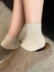 Close-up detail of thin cotton short socks in creamy coffee color, styled with cozy shoes.