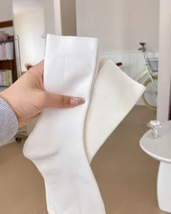 Close-up view of clean white cotton mid-tube stack socks displayed in a cozy room setting.