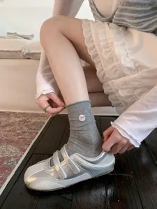 Chaussettes mi-mollet grises pour femmes avec broderie de nœud rose, coton doux, détail mode.