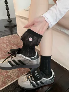 Gros plan de chaussettes mi-hautes en dentelle noire avec un joli motif de nœud papillon rose.