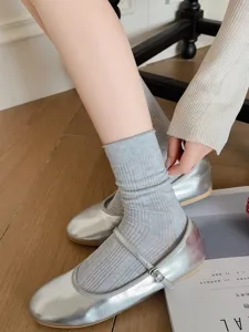 Close-up detail of breathable ribbed grey crew socks paired with shiny silver Mary Jane flats.