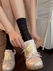 Detailed view of women's hollow breathable mid-tube socks paired with cute bow sneakers.