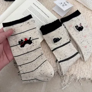 Close-up of cute cat embroidered mid-calf socks, flecked yarn fabric with black ribbed cuffs.