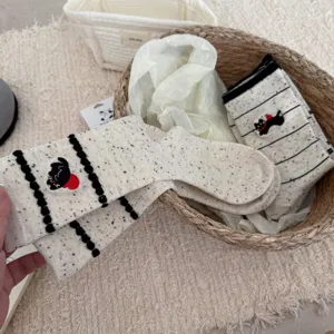 Close-up detail of cute cartoon embroidered speckled yarn mid-calf socks in basket display.