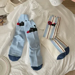 Close-up detail of cute cartoon cat and striped mid-calf socks for women, soft cotton daily wear.