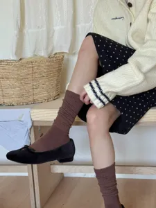 Dettaglio di comodi calzini lunghi marroni abbinati a scarpe basse per look autunnali casual.