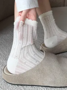 Close-up shot of white sheer mesh mid-tube socks with delicate lace ruffles and cute dot patterns.
