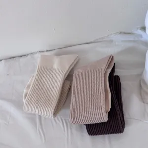 Dettaglio di calze a costine in tonalità neutre, che mostra la trama della maglia in cotone.
