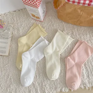 Detailed shot of solid color ribbed mid-tube slouch socks with rolled cuffs in soft pastel tones.