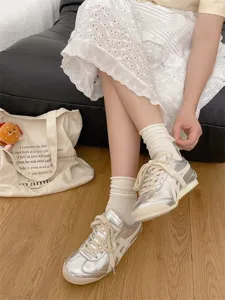 Detail shot of solid color ribbed slouch socks paired with stylish metallic sneakers and dress.