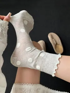 Close-up view of sheer summer mesh socks with cute polka dots and delicate ruffled lace cuffs.
