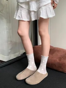 Detailed view of white sheer mesh polka dot socks with cute ruffled lace trim edges.
