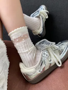 Close-up detail of sheer white mesh polka dot mid-tube socks with delicate lace ruffle trim.