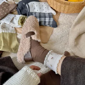Cozy fuzzy slippers and knitted slouchy socks detail shot showing soft warm winter texture.