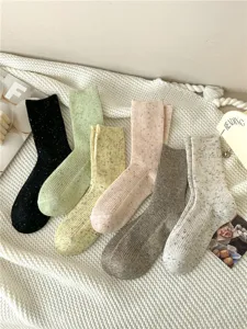 Detailed view of thick wool blend speckled knit crew socks in assorted cream and pastel colors.