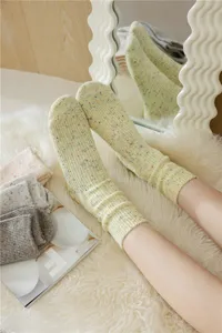 Close-up of thick wool-blend slouch socks with colorful speckles, soft ribbed knit texture.