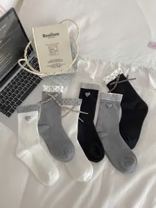 Cozy women mid-tube socks with cute heart bow accents, soft cotton knit for autumn and winter.