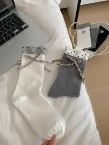 Detailed shot of cute women mid-calf socks with polka dot cuff and plaid bow design.