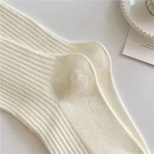 Primo piano dettagliato di morbidi calzini a coste in bianco crema con trama fine.