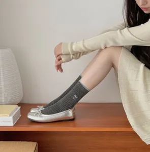 Detailed shot of grey ribbed stack socks featuring blue contrast trim and cute embroidered bow.