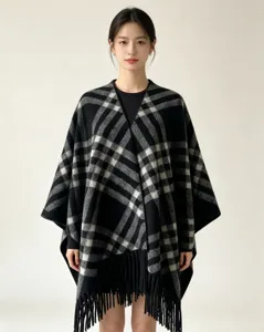 Black and white plaid poncho detail, showing the soft tassel hem and warm winter fabric.