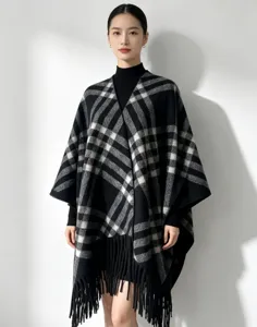 Detailed view of the elegant black and white plaid tassel poncho cape worn by model.