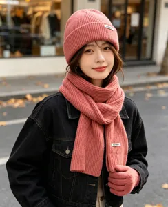 Detailed view of women's winter pink knitted beanie hat scarf and gloves three-piece set.