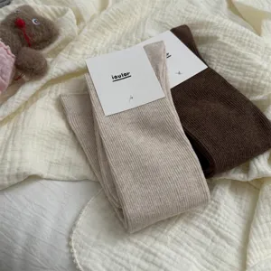Scatto dettagliato di comodi calzini slouch a coste in cotone beige e marrone con etichette.