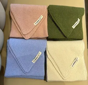 Detailed shot of soft chunky knit mini scarves in four chic colors with woven brand labels.