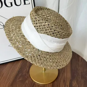 Primo piano dettaglio del cappello di paglia naturale vintage con elegante nastro bianco.