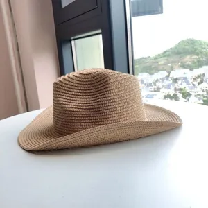 Vista detallada de un sombrero de paja beige con ala enrollada, ideal para la playa.