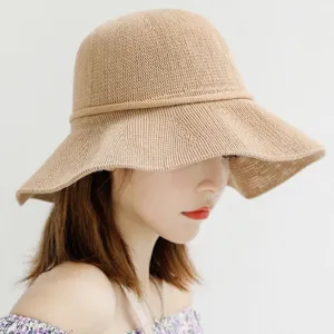Detailed view of women's beige straw sun hat, showing fine knit texture and wide brim style.